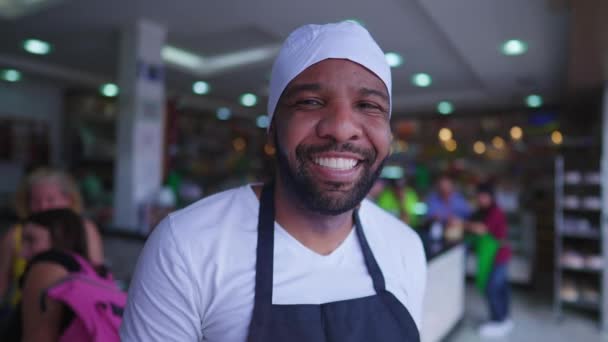 一个年轻快乐的黑人餐厅职员穿着围裙和发帽站在餐厅里的画像 一名快乐的非裔美国人雇员的特写 — 图库视频影像