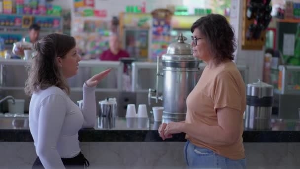 デリのカフェテリアカウンターで話している2人の女性 率直な対話 小規模ビジネスレストラン内でおしゃべり — ストック動画