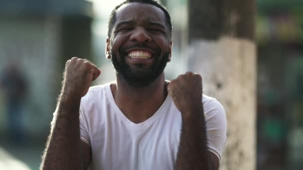 一个兴奋的黑人庆祝成功 在黎明时分 站在城市的环境中 高高兴兴地举起双手 — 图库视频影像