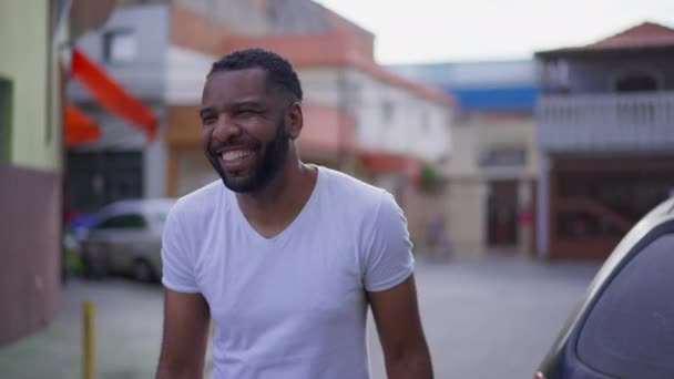 街の通りの外に立っている間に笑って笑って笑っている1人の喜び黒人男性 フレンドリーなカリスマ的表現で幸せなアフリカ系アメリカ人 — ストック動画
