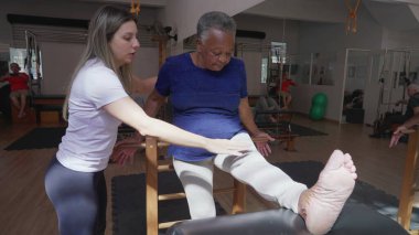 Siyahi Kıdemli Kadın Pilates Koçu Eğitimi Altında Vücut Germe, Fizyoterapi Rehabilitasyon Seansı