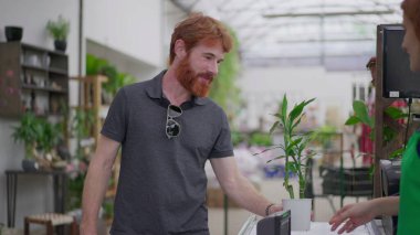 Genç Adam Çiçek Dükkanı 'nda Bitki Satın Alma ve Telefonu Tap to Tap-to-Pay için kullanıyor. Bahçecide Kusursuz Temassız Ödeme