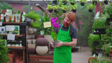 Bahçecide elinde çiçekle gülümseyen genç adam. Yerel Markette Yeşil Önlüklü Kızıl Saçlı Çalışan