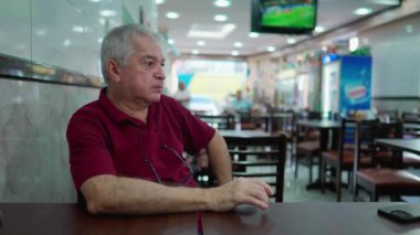 Brezilya kafeteryasında oturan dalgın bir son sınıf öğrencisi. 70 'lerdeki düşünceli yaşlı insan restoran işinde kafa yoruyor.
