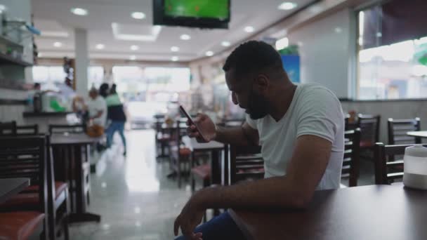 Svart Man Tittar Telefonskärmen Sitter Inne Traditionella Brasilianska Cafeteria Företag — Stockvideo
