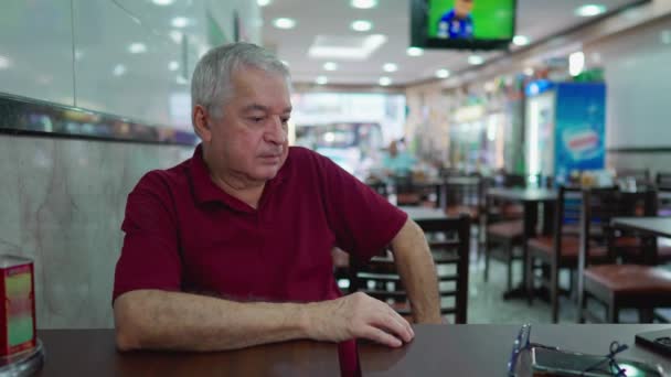 Ένας Σκεπτικός Ηλικιωμένος Που Κάθεται Μια Επιχείρηση Εστιατορίων Προκατειλημμένο Άτομο — Αρχείο Βίντεο