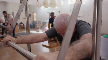 Pilates makinesiyle egzersiz yapan yaşlı adam. Yaşlılık egzersizi, omurga sağlığı egzersizi.
