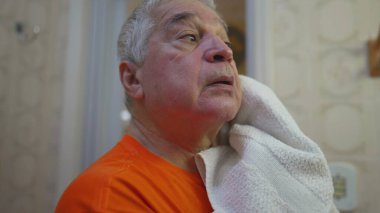 Kıdemli adam sabah rutininden sonra yüzünü havluyla kuruladı.