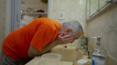 Banyoda yüzünü yıkayan kıdemli bir adam, ev hayatı sabah rutini. Yaşlı Adam Tazeleniyor