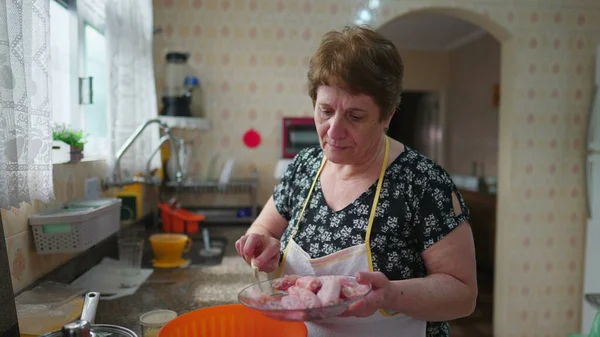 老年妇女在真实的家庭生活场景中做饭 老年人在碗里放鸡做饭 — 图库照片
