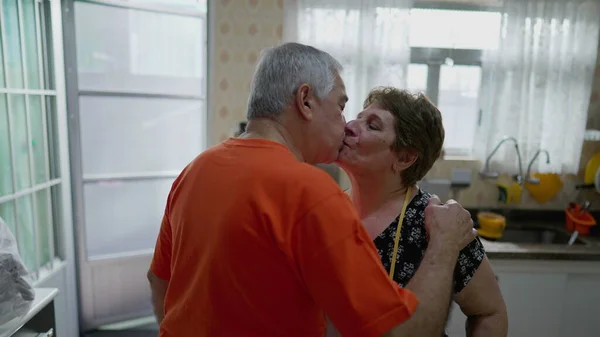 Senior Couple Sharing Morning Goodbye Kiss Kitchen Tender Moment Tussen — Stockfoto