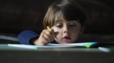 Samimi küçük çocuk evde okul aktivitesi yapıyor. Çocuk yuvası. Kağıt üzerinde kalem tutan yakın plan yüz.
