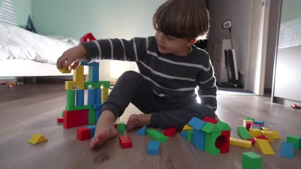 小孩在地板上玩积木 孩子的生活方式意外地摧毁了塔楼 一个小男孩在卧室里玩耍 — 图库视频影像