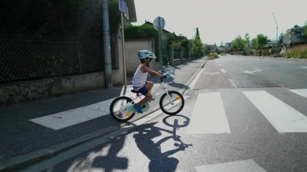 子供は自転車で通りを横断する 週末のアクティビティを楽しむ保護ヘルメットを身に着けている街の横断歩道で1人の小さなスポーツ少年 — ストック動画