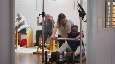 Kadın pilates koçu grup sınıfında siyahi bir kadına yardım ediyor. Sağlık hizmetleri spor eğitmeninin gizli bir sahnesi.
