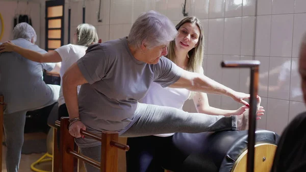 Female Pilates Coach Guiding Senior Woman Stretch Body Physiotherapy Class — Stock Photo, Image