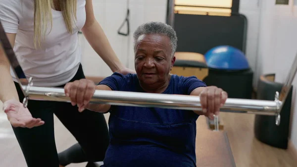 Female Pilates Coach Assisting Black Senior Woman Use Machine Old — Stock Photo, Image