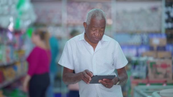 一位巴西杂货店的黑人高级经理摆着平板电脑在小商店里拍照 使用现代技术的非洲裔美国老年人 — 图库视频影像