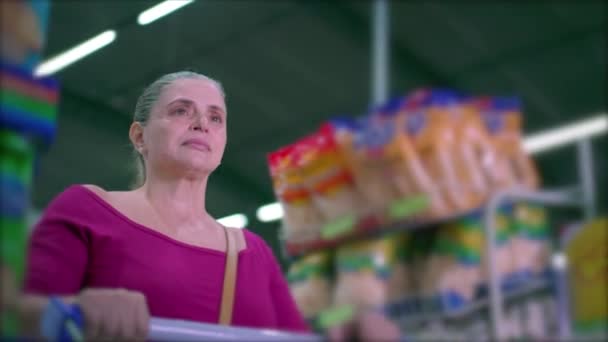 女购物者走在杂货店的过道上 推着购物车寻找商品 描绘了消费者的生活习惯 — 图库视频影像