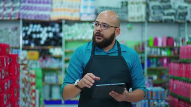 食料品店通路を歩くスーパーマーケットの幸せな従業員タブレットデバイスを保持在庫確認ブラウジング製品 — ストック動画