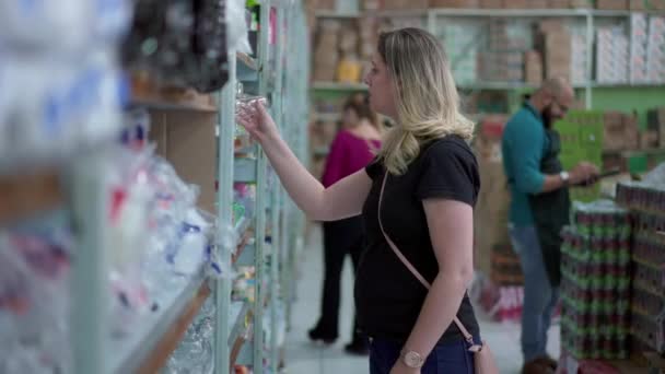 Vrouw Browsing Products Bij Supermarkt Depicting Consumer Lifestyle Picks Item — Stockvideo
