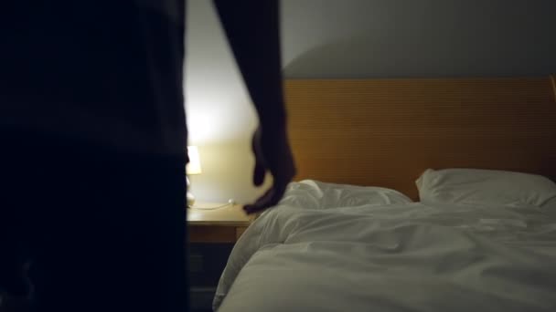 人经过漫长的一天躺在床上休息 躺在床单下睡觉的人把床头灯关了 — 图库视频影像