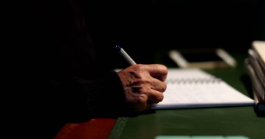 Düşünceli yaşlı kadın geceleri masa başında oturup notlar yazıyor.