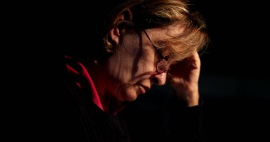 Düşünceli yaşlı kadın geceleri masa başında oturup notlar yazıyor.