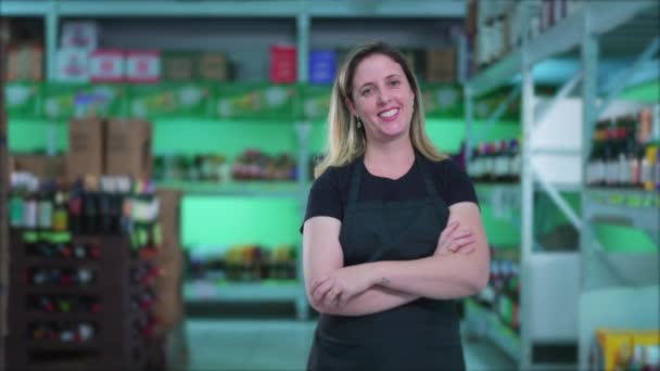 快乐女店员站在超级市场的过道上 双手交叉 微笑着坐在产品旁边 — 图库视频影像
