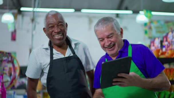 古いスーパーマーケットの同僚の間で真の喜びは タブレットデバイス 成功を祝う労働者と高5 笑顔多様なシニア男性を行う — ストック動画