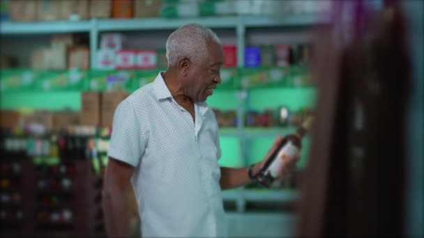 アフリカ系アメリカ人の高齢者が食料品店の棚から飲料を選ぶことができた スーパーでのアルコール飲料のための一つのシニア黒人男性ショッピング — ストック動画