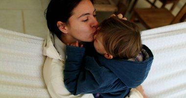 Anne hamakta oğlunu öpüyor.