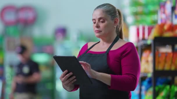 タブレットデバイスを使用してスーパーの女性労働者 現代的な技術チェック在庫を使用して中年の女性スタッフ — ストック動画
