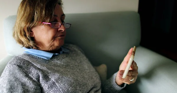 Wanita Senior Menonton Konten Pada Perangkat Smartphone Duduk Sofa — Stok Foto