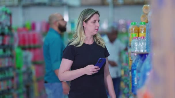 Kobieta Sprawdzanie Listy Zakupów Telefonie Podczas Przeglądania Soda Aisle Ukryta — Wideo stockowe