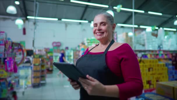 タブレット付きスーパーマーケットの女性スタッフ 笑顔の幸せな表情 ビジネス内の中年の従業員 — ストック動画