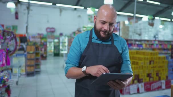スーパーマーケットチェーン内の在庫状況を確認するタブレットデバイスを使用して食料品店のブラジルの従業員は エプロンを着用し 仕事に従事 — ストック動画