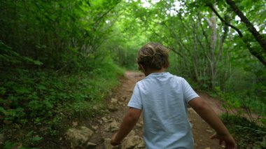 Doğada oynayan çocuk orman yolunda koşuyor.