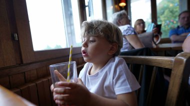 Restoranda samanla içki içen bir çocuk yemek sırasında meyve suyu içer.