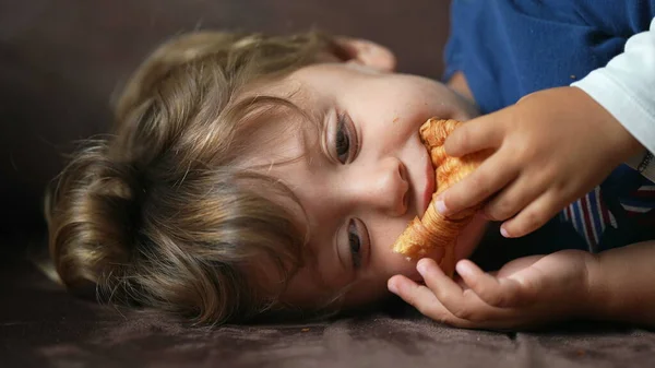 Dziecko Jedzące Croissant Jeden Mały Chłopiec Leżący Kanapie Jedzenie Węglowodanów — Zdjęcie stockowe