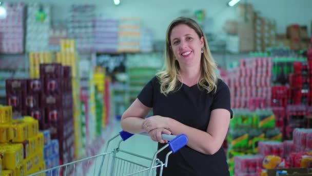 女购物者站在超市过道上 购物车在镜头前微笑 一位40多岁的高加索女性消费者 — 图库视频影像