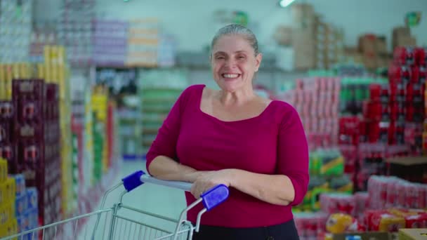 在超级市场用购物车微笑中老年女性消费者 描绘消费主义的生活方式习惯 — 图库视频影像