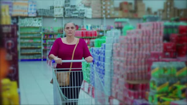 棚の上のスーパーマーケットの通路ブラウジング製品で女性の消費者歩く ショッピングカートを押す中年の買い物客 — ストック動画