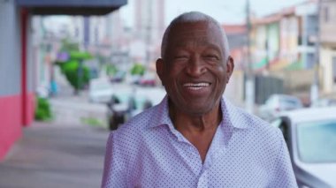 Caddede dikilip gülümseyen bir ifadeyle kameraya bakan mutlu siyah Brezilyalı bir adamın portresi. Şehir ortamında neşeli duyguları olan yaşlı Afrikalı Amerikalı erkek.