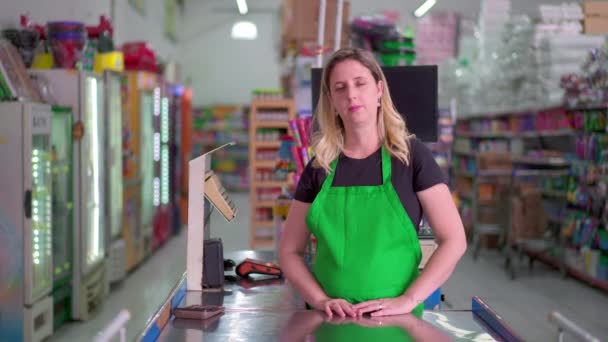 Женщина Работница Супермаркета Стоит Кассы Смотрит Камеру Нейтральным Выражением Лица — стоковое видео