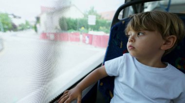 Genç çocuk trenle seyahat eder, yolcu koltuğunda oturur, camdan bakar gibi.