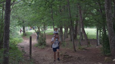 Baba ve çocuk birlikte doğa yürüyüşü. Oğul baba omuzlarında.