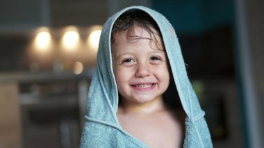 Havluyla kaplı şirin bir çocuk. Banyodan sonra kameraya gülümseyen sevimli bir bebek.