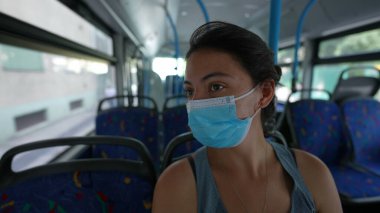 Toplu taşıma içinde yüz maskesi takan bir kadın.