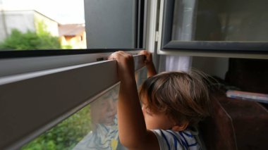 Pencereye yakın duran çocuk, pencerenin yanındaki küçük tehlikeli çocuk, evin dışındaki kazayı görmek istiyor.